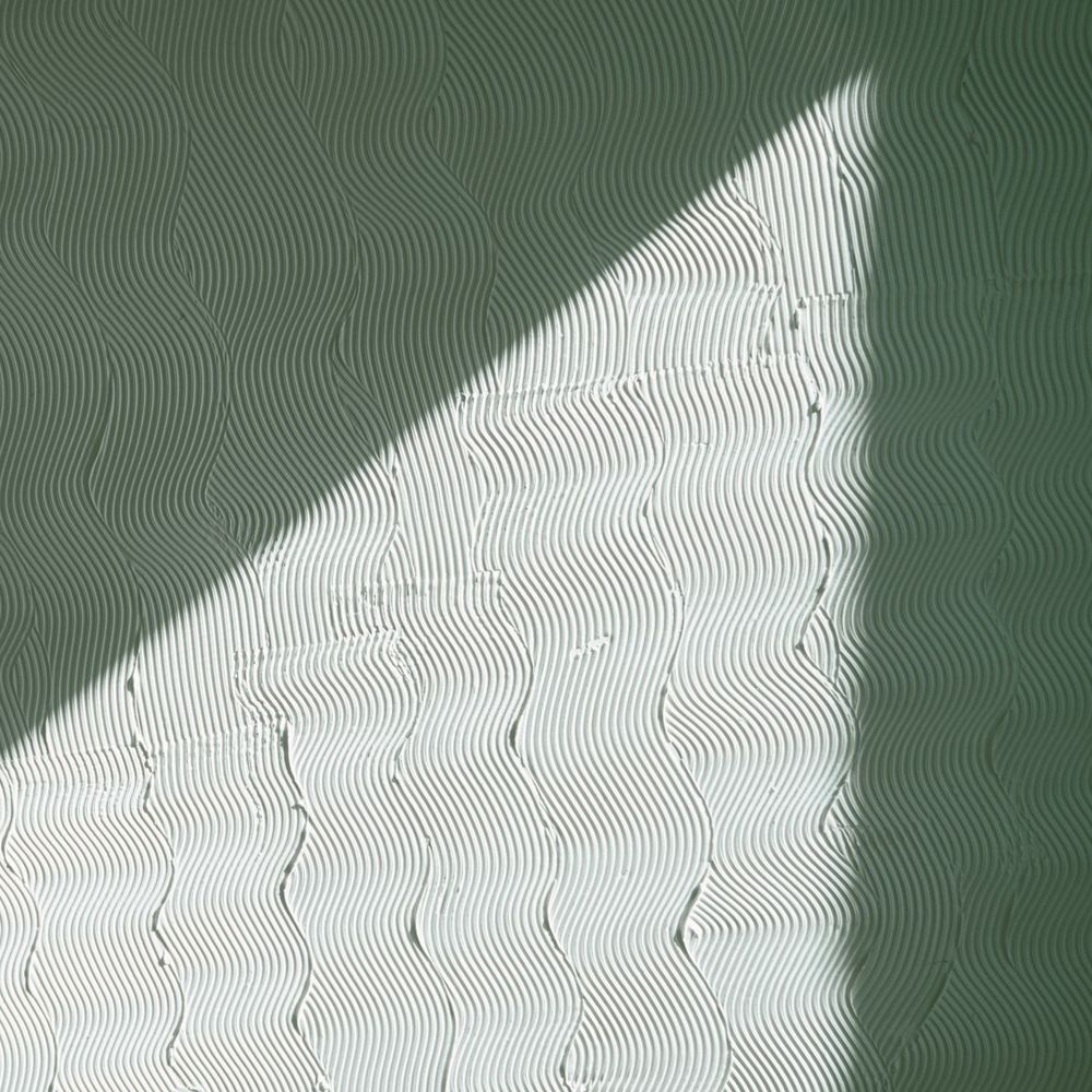 Hand-worked green lime plaster, half in diagonal sunlight.