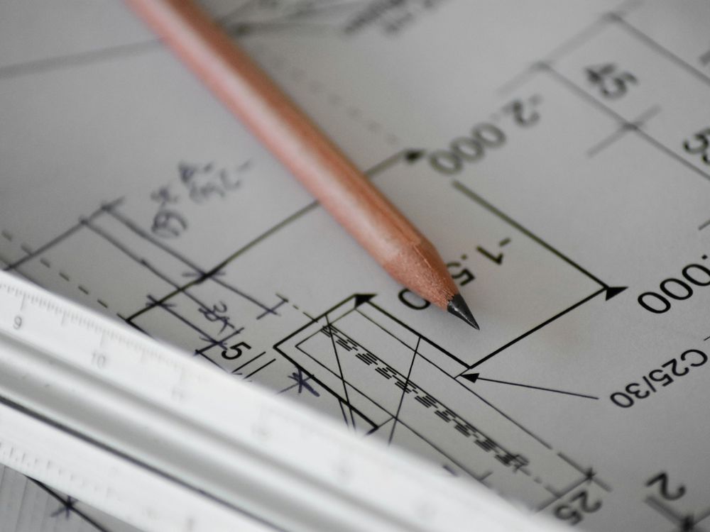 Pencil resting on a technical drawing with dimension lines