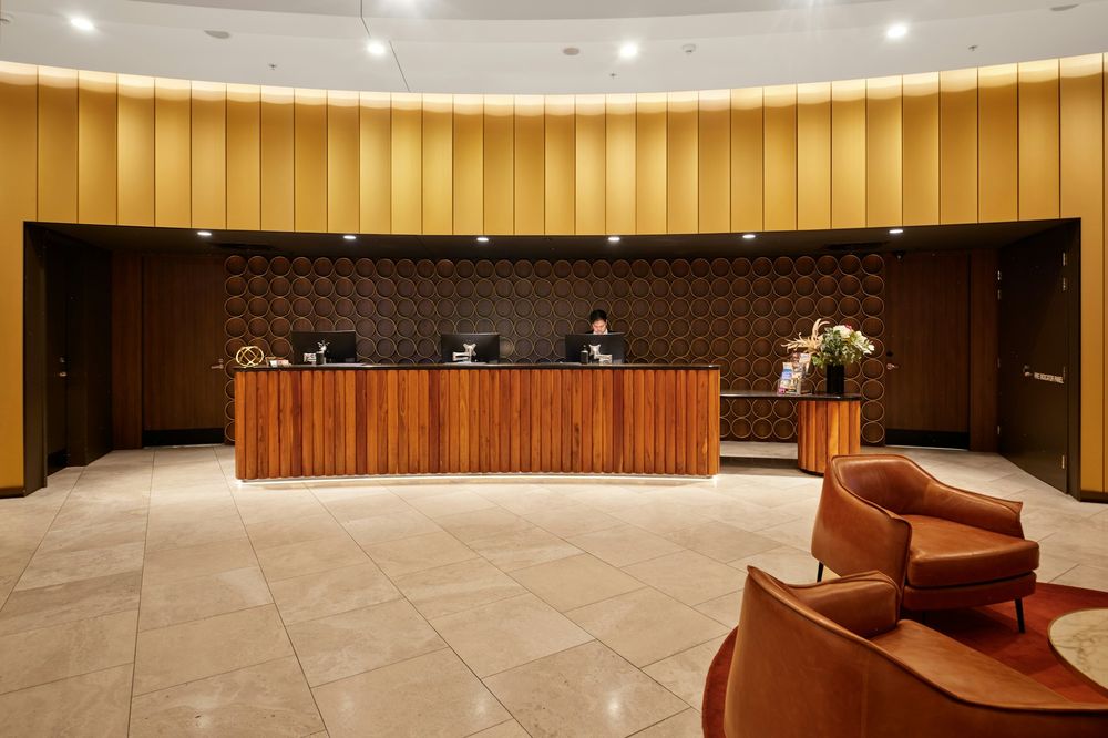 Hotel reception desk in front of a curved wall of golden wood panels
