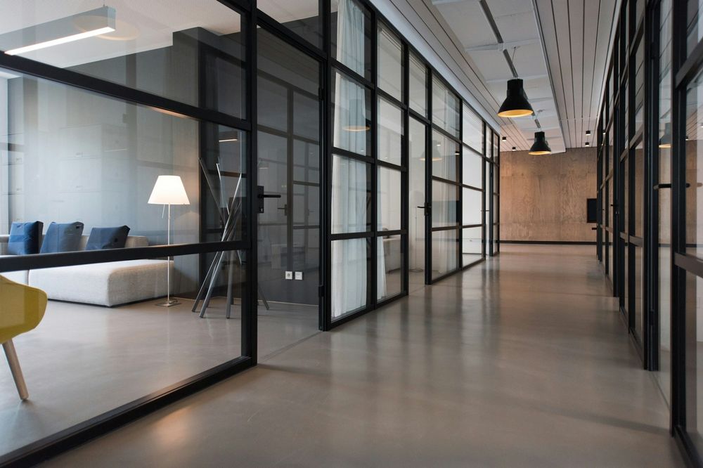 Office corridor lined with black-framed glass partitions