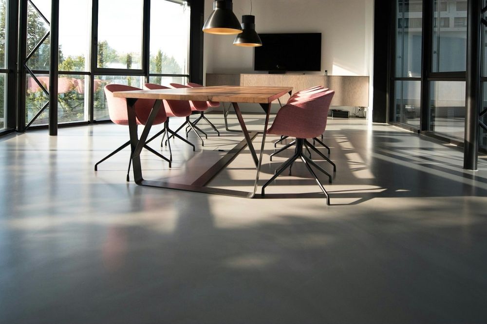 Open-plan office with floor-to-ceiling glass, a long table and a polished concrete floor