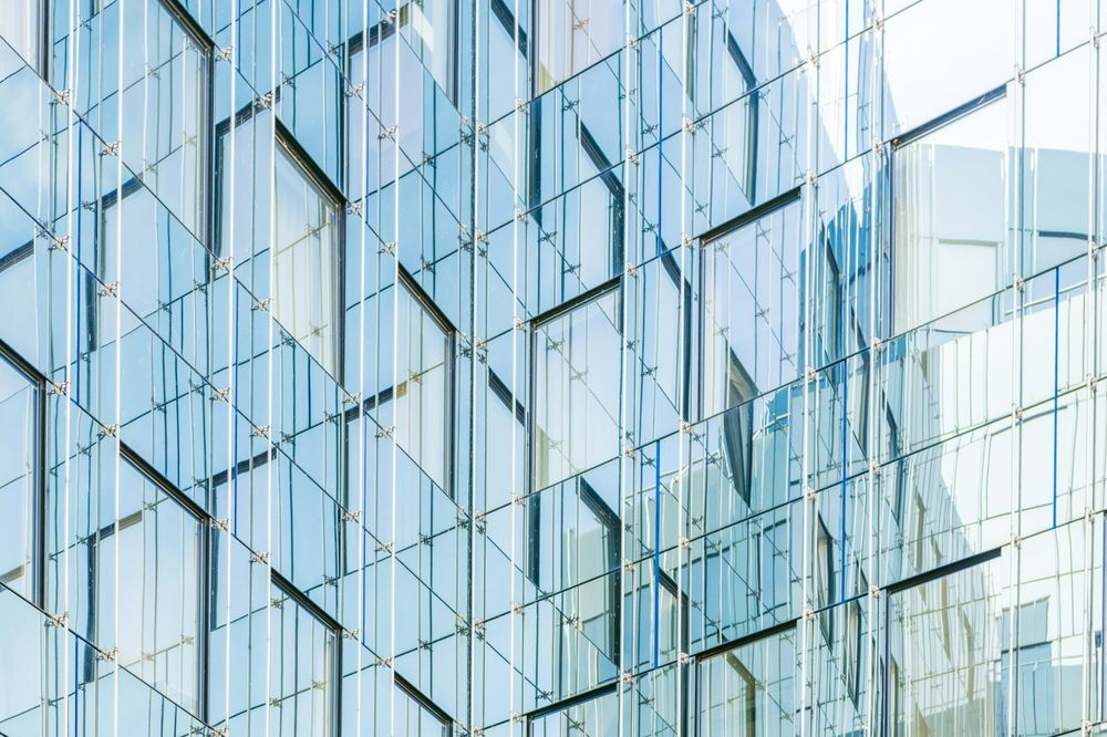 Glass curtain-wall façade reflecting the sky
