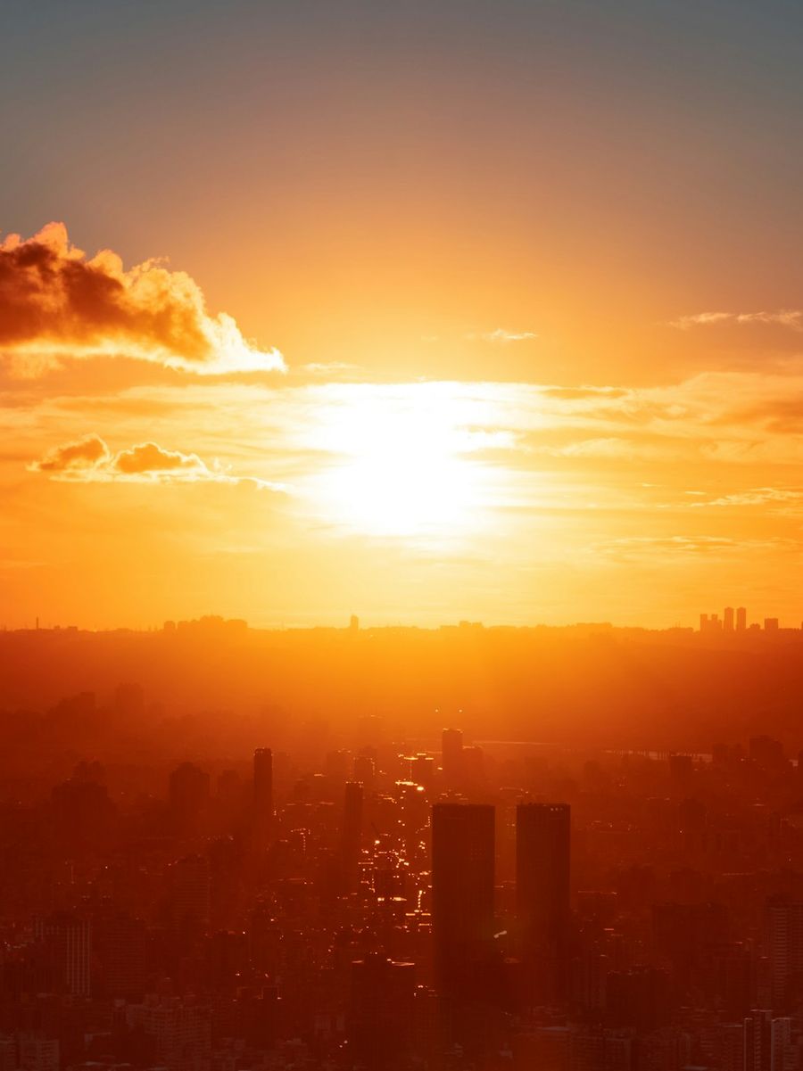 A large orange sun setting over a hazy city.