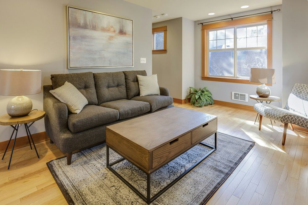 A living room with a grey sofa, a wooden coffee table and a sunny window
