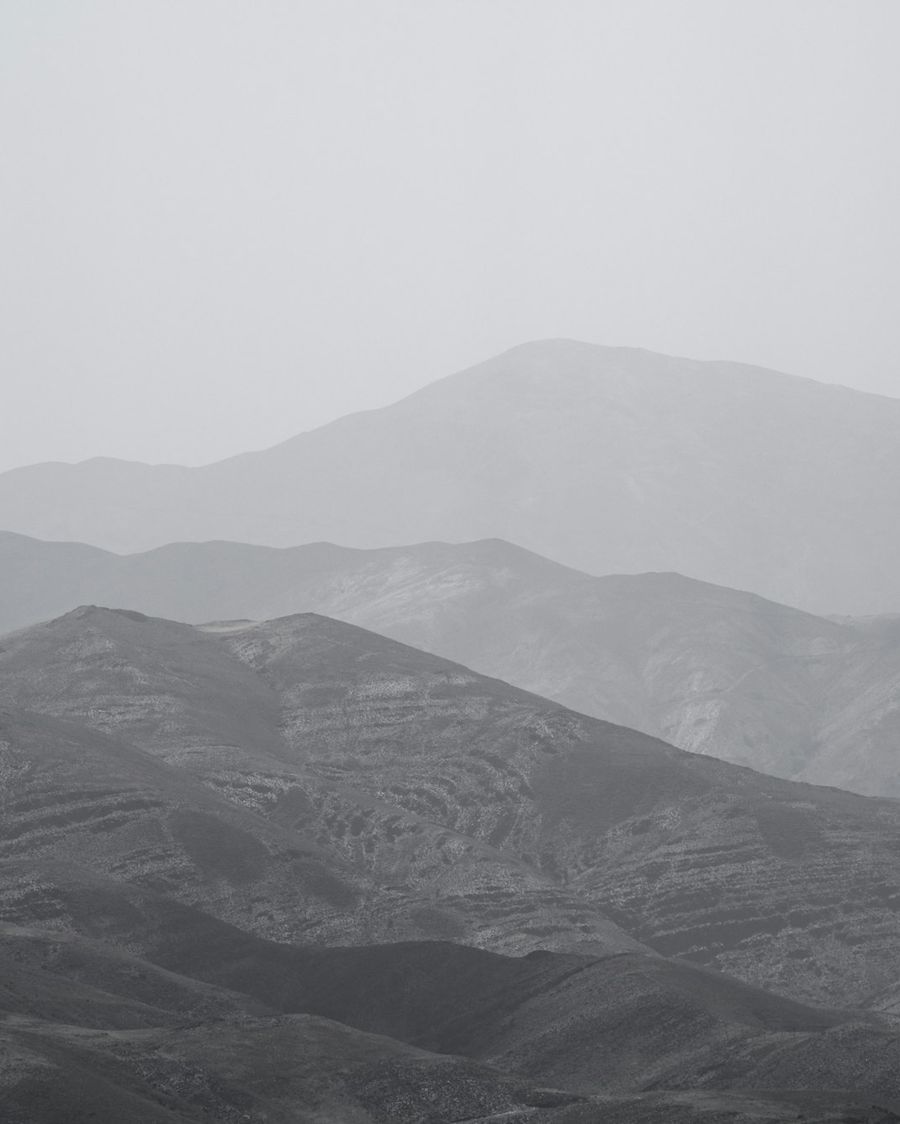 Grey mountain ridges fading into haze, one behind another