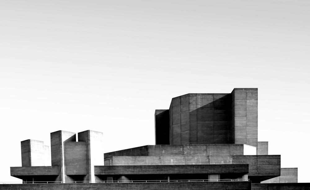 Stacked concrete volumes of a brutalist theatre against a pale sky.