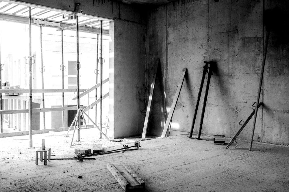 Unfinished concrete room with steel props and scaffolding leaning on the walls.