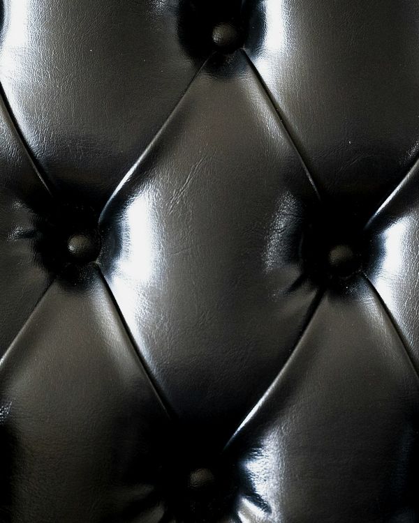 Close-up of glossy black buttoned leather.